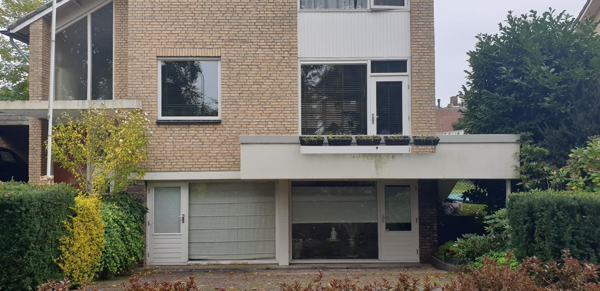 De praktijk van buiten: de ingang van de spreekkamer in het souterrain, omgeven door groen